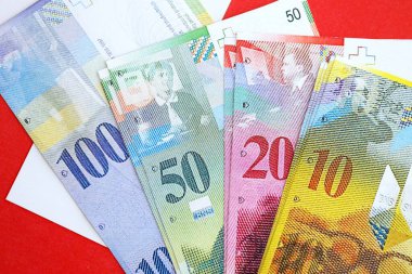 İsviçre frangı banknotları ve bayrağı. Mevcut para banknotları büyük miktarda bayrağın üzerinde yatıyor. İsviçre 'de iş ve yatırım kavramı