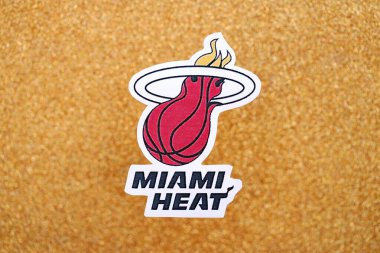 KYIV, UKRAINE - 23 Şubat 2025 Miami Heat basketbol takımı rozeti altın sarısı parıltılı arka plan afişinde yatıyor