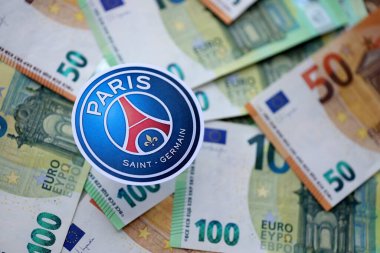 KYIV, UKRAINE - 23 Şubat 2025 Paris Saint Germain FC futbol kulübü rozeti büyük miktarda EURO para banknotları üzerinde yatıyor