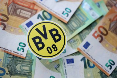 KYIV, UKRAINE - 23 Şubat 2025 Borussia Dortmund futbol kulübü rozeti büyük miktarda EURO para banknotlarının üzerinde yatıyor