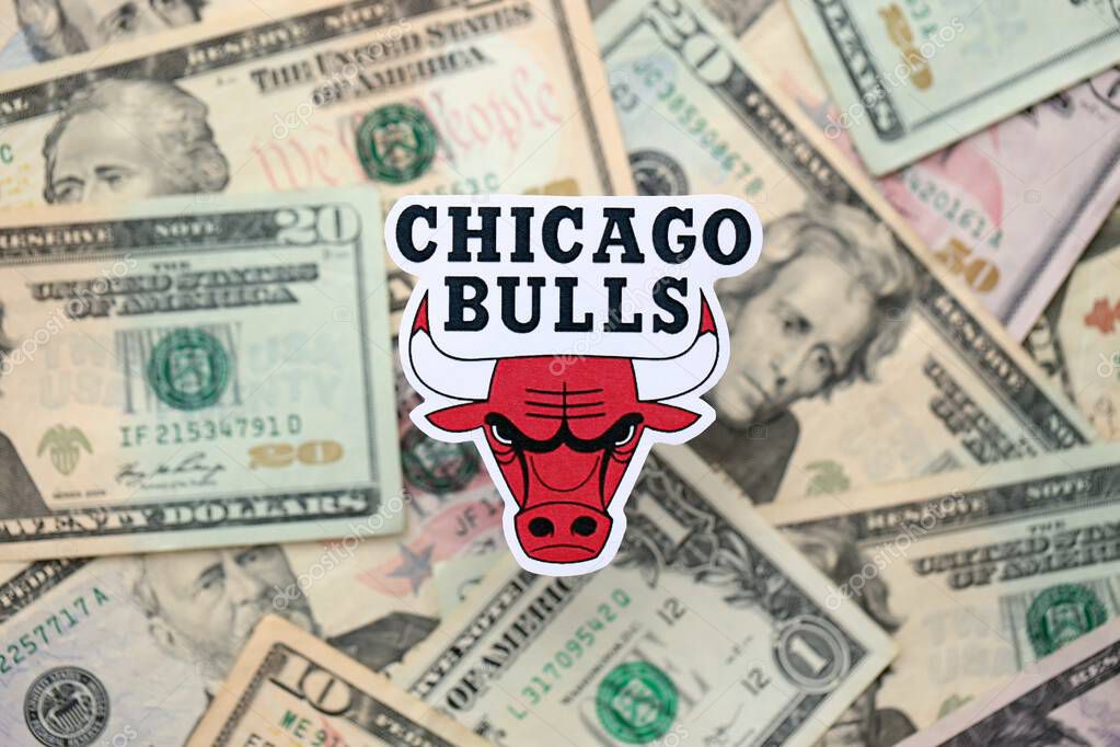 KYIV, UKRAINE - FEBRUARY 23, 2025 Chicago Bulls basketball team badge lies on big amount of US dollar bills close up