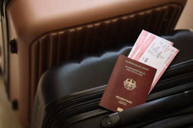 Biletli Almanya pasaportu havaalanındaki bekleme salonunda duran turistik bavulun üzerinde yatıyor. Dünya çapında seyahat ve uluslararası turizm kavramı