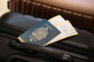 Biletli Kanada pasaportu havaalanı bekleme salonundaki turistik bavulun üzerinde yatıyor. Dünya çapında seyahat ve uluslararası turizm kavramı