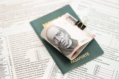 Meksika Pezosu 'nun büyük meblağlı para faturaları pasaport ve vergi formlarıyla birlikte masanın üzerinde duruyor. Maliye ve vergi ödeme kavramı