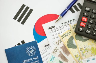 Güney Kore büyük miktarda para kazandı. Masada kalem, hesap makinesi, pasaport ve vergi formları var. Vergi ödeme ve muhasebe kavramı