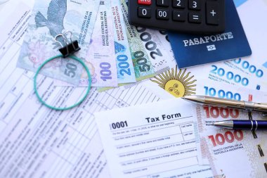 Arjantin Pezosu 'nun para faturaları kalem, hesap makinesi, pasaport ve vergi formlarıyla dolu. Finans ve bankacılık kavramı