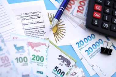 Arjantin Pezosu 'nun para faturaları kalem, hesap makinesi, pasaport ve vergi formlarıyla dolu. Finans ve bankacılık kavramı