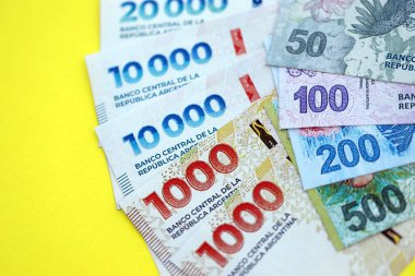 Arjantin pezosu büyük miktarlarda banknotlar sarı renkli masaya yakın duruyor. Finans ve bankacılık kavramı
