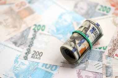 Bir tomar Amerikan doları büyük miktarda Brezilya banknotlarının üzerinde yatıyor. Amerikan parası Brezilya 'nın para akışında yatıyor. Brezilya 'da ekonomi ve döviz kuru kavramı