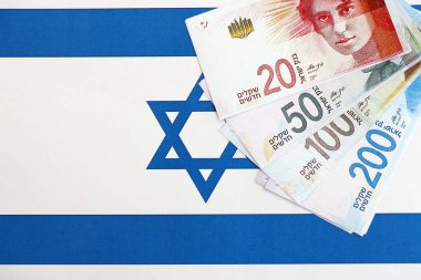 Israel New Shekels banknotları ulusal bayrak üzerinde. İsrail 'in şu anki para faturaları büyük oranda bayrağın üzerinde yatıyor. İsrail 'de iş ve yatırım kavramı