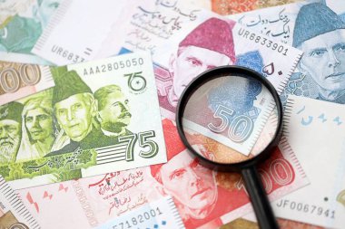 Pakistan banknotları ve büyüteç. Pakistan 'ın mevcut para ve büyüteç faturaları büyük miktarda masanın üzerinde duruyor. Pakistan 'da mali izleme ve vergilendirme kavramı