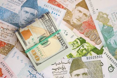 Bir sürü Amerikan doları Pakistan Rupileri 'nin banknotlarına yakın duruyor. Amerikan para demeti Pakistan 'ın para banknotlarında yatıyor. Pakistan 'da ekonomi ve döviz kuru kavramı