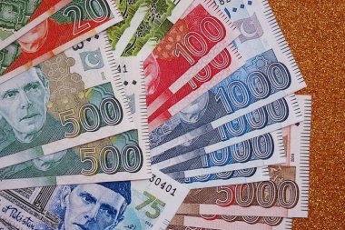 Pakistan altın sarısı arka planda banknotlar halinde. Pakistan 'ın mevcut para faturaları büyük miktarda masada yatıyor. Pakistan 'da iş ve yatırım kavramı