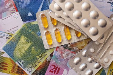 İsviçre frangı ve ilaç hapları. Mevcut para ve uyuşturucu banknotları büyük miktarda masada yatıyor. İsviçre 'de ilaç ve eczane kavramı