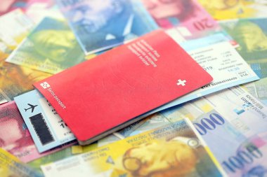 İsviçre frangı banknotları ve biletli pasaport. Mevcut banknotlar ve biyometrik geçiş kartları büyük miktarda masada yatıyor. İsviçre 'de seyahat ve tatil kavramı