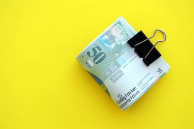 Sarı arka planda İsviçre frangı banknotları. Mevcut frank para faturaları büyük miktarda masada yatıyor. İsviçre 'de iş ve yatırım kavramı