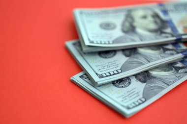 Kırmızı arka planda büyük miktarda yüz dolarlık banknot var. ABD 'de vergilendirme ve para yapma kavramı