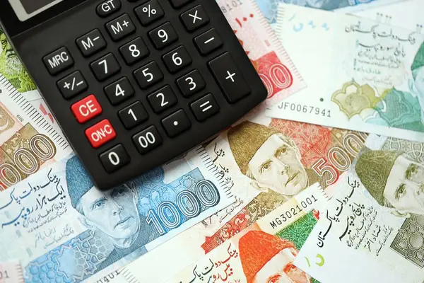 Pakistan banknotları ve hesap makinesi. Pakistan 'ın mevcut para ve hesap makinesi büyük miktarda masada yatıyor. Pakistan 'da vergi ve para sayımı kavramı