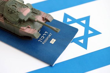 Bayrakta İsrail pasaportu ve oyuncak tank. Geçerli İsrail pasaportu ve tankı bayrağın üzerinde duruyor. İsrail 'de ordu fonları ve silah satışları kavramı
