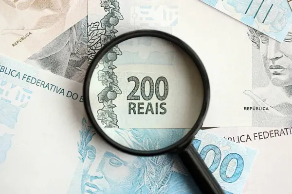 Brezilya reais banknotları ve büyüteç. Mevcut Brezilya gerçek para faturaları ve loupe büyük miktarda masada yatıyor. Brezilya 'da mali izleme ve vergilendirme kavramı