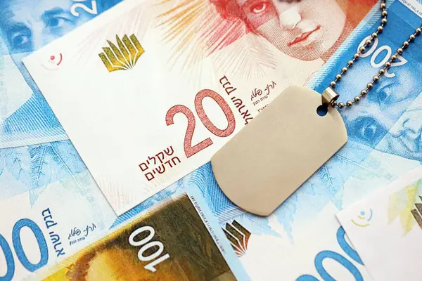 İsrail Yeni Şekelleri 'nin banknotları ve askeri simgesi. İsrail 'in mevcut para faturaları ve künyeleri büyük miktarda masada yatıyor. İsrail 'de askerlik kavramı