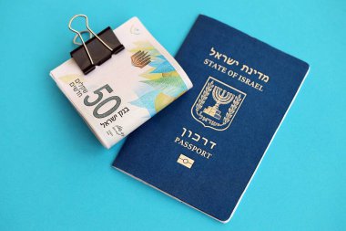 Israel New Shekels banknotları ve mavi arka planda pasaport. İsrail 'in şu anki para banknotları büyük oranda mavi üzerine yatar. İsrail 'de finans ve nakit kavramı