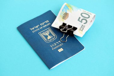 Israel New Shekels banknotları ve mavi arka planda pasaport. İsrail 'in şu anki para banknotları büyük oranda mavi üzerine yatar. İsrail 'de finans ve nakit kavramı