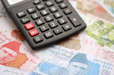 Pakistan banknotları ve hesap makinesi. Pakistan 'ın mevcut para ve hesap makinesi büyük miktarda masada yatıyor. Pakistan 'da vergi ve para sayımı kavramı