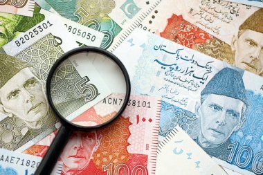 Pakistan banknotları ve büyüteç. Pakistan 'ın mevcut para ve büyüteç faturaları büyük miktarda masanın üzerinde duruyor. Pakistan 'da mali izleme ve vergilendirme kavramı