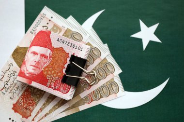 Pakistan bayrağı üzerinde Pakistan banknotları. Pakistan 'ın mevcut para faturaları büyük miktarlarda pankartta yatıyor. Pakistan 'da ekonomi ve ticaret kavramı