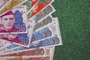 Pakistan parlayan yeşil arka planda banknotlar halinde. Pakistan 'ın mevcut para faturaları büyük miktarda masada yatıyor. Pakistan 'da iş ve yatırım kavramı