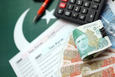 Pakistan hesap makinesi ve vergi formuyla banknotlar halinde. Şu anki Pakistan gerçek para ve vergi faturaları yakın plan. Pakistan 'da vergi ödeme ve muhasebe kavramı