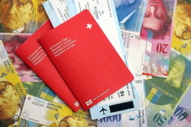 İsviçre frangı banknotları ve biletli pasaport. Mevcut banknotlar ve biyometrik geçiş kartları büyük miktarda masada yatıyor. İsviçre 'de seyahat ve tatil kavramı