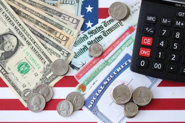 Amerikan doları para faturaları, sosyal güvenlik numarası ve Amerikan bayrağındaki hesap makinesi yakın plan. Vergi ödeme ve sigorta kavramı