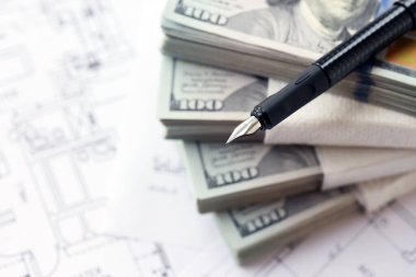 Kalemle birlikte yüklü miktarda Amerikan doları banknotları ve konut projesinin planları yakın plan. Yatırım ve inşaat projesi kavramı