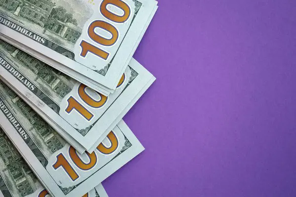 Mor arka planda büyük miktarda yüz dolarlık banknotlar. ABD 'de vergilendirme ve para yapma kavramı