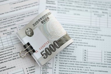 Kuzey Kore büyük miktarlarda para kazandı. Masada vergi formları var. Muhasebe ve vergilendirme kavramı