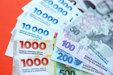Arjantin pezosu büyük miktarlarda para kırmızı renkli masaya yakın duruyor. Finans ve bankacılık kavramı