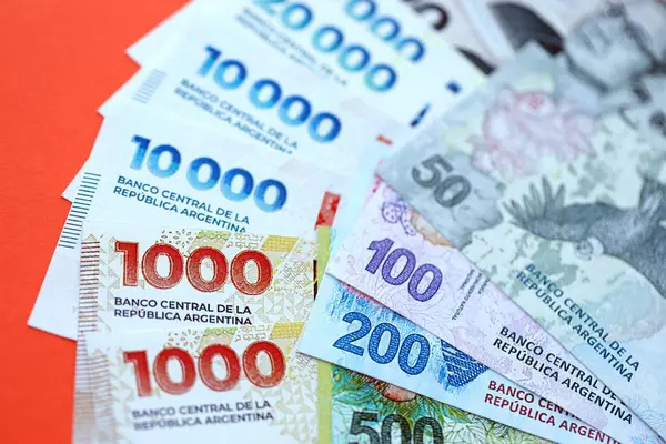 Arjantin pezosu büyük miktarlarda para kırmızı renkli masaya yakın duruyor. Finans ve bankacılık kavramı