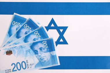 Israel New Shekels banknotları ulusal bayrak üzerinde. İsrail 'in şu anki para faturaları büyük oranda bayrağın üzerinde yatıyor. İsrail 'de iş ve yatırım kavramı