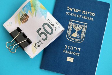 Israel New Shekels banknotları ve mavi arka planda pasaport. İsrail 'in şu anki para banknotları büyük oranda mavi üzerine yatar. İsrail 'de finans ve nakit kavramı