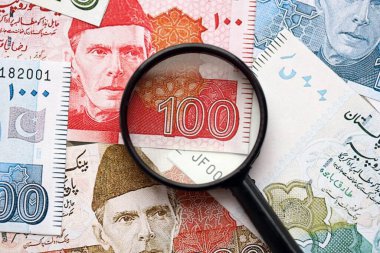 Pakistan banknotları ve büyüteç. Pakistan 'ın mevcut para ve büyüteç faturaları büyük miktarda masanın üzerinde duruyor. Pakistan 'da mali izleme ve vergilendirme kavramı