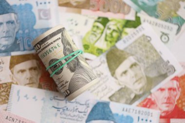 Amerikan dolarlarının rulosu Pakistan 'daki büyük miktardaki banknotların üzerinde yatıyor. Amerikan para demeti Pakistan 'ın para banknotlarında yatıyor. Pakistan 'da ekonomi ve döviz kuru kavramı