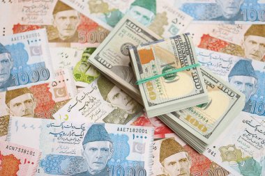 Amerikan dolarları yığını Pakistan Rupi banknotlarının büyük bir miktarına yakın duruyor. Amerikan para demeti Pakistan 'ın para banknotlarında yatıyor. Pakistan 'da ekonomi ve döviz kuru kavramı