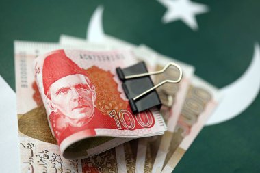 Pakistan bayrağı üzerinde Pakistan banknotları. Pakistan 'ın mevcut para faturaları büyük miktarlarda pankartta yatıyor. Pakistan 'da ekonomi ve ticaret kavramı