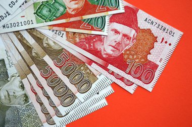 Pakistan kırmızı arka planda banknotlar halinde. Pakistan 'ın mevcut para faturaları büyük miktarda masada yatıyor. Pakistan 'da iş ve yatırım kavramı
