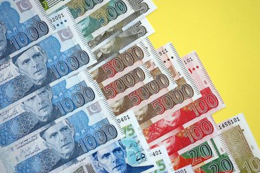 Pakistan banknotları sarı arka planda. Pakistan 'ın mevcut para faturaları büyük miktarda masada yatıyor. Pakistan 'da iş ve yatırım kavramı