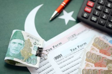Pakistan hesap makinesi ve vergi formuyla banknotlar halinde. Şu anki Pakistan gerçek para ve vergi faturaları yakın plan. Pakistan 'da vergi ödeme ve muhasebe kavramı