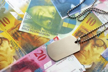 İsviçre frangı banknotları ve askeri jeton. Mevcut banknotlar ve künyeler masanın üzerinde büyük miktarda duruyor. İsviçre 'de askerlik konsepti