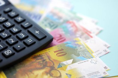 İsviçre frangı banknotları ve hesap makinesi maviye. Mevcut frank para faturaları ve calc büyük miktarda masada yatıyor. İsviçre 'de vergilendirme ve para konsepti